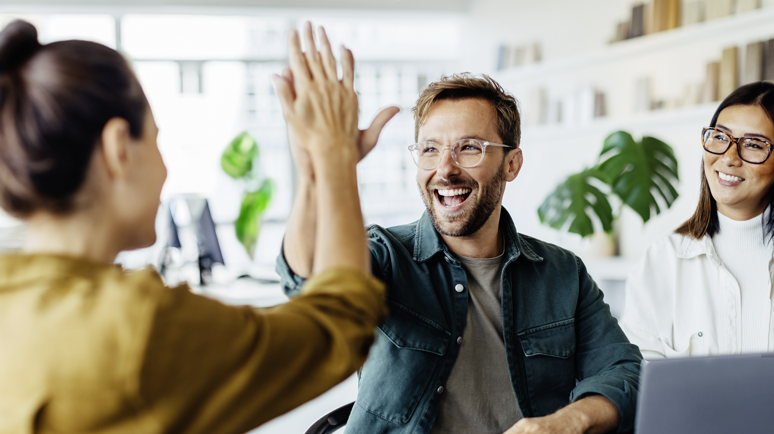 Drei glückliche Menschen, von denen sich zwei ein highfive geben